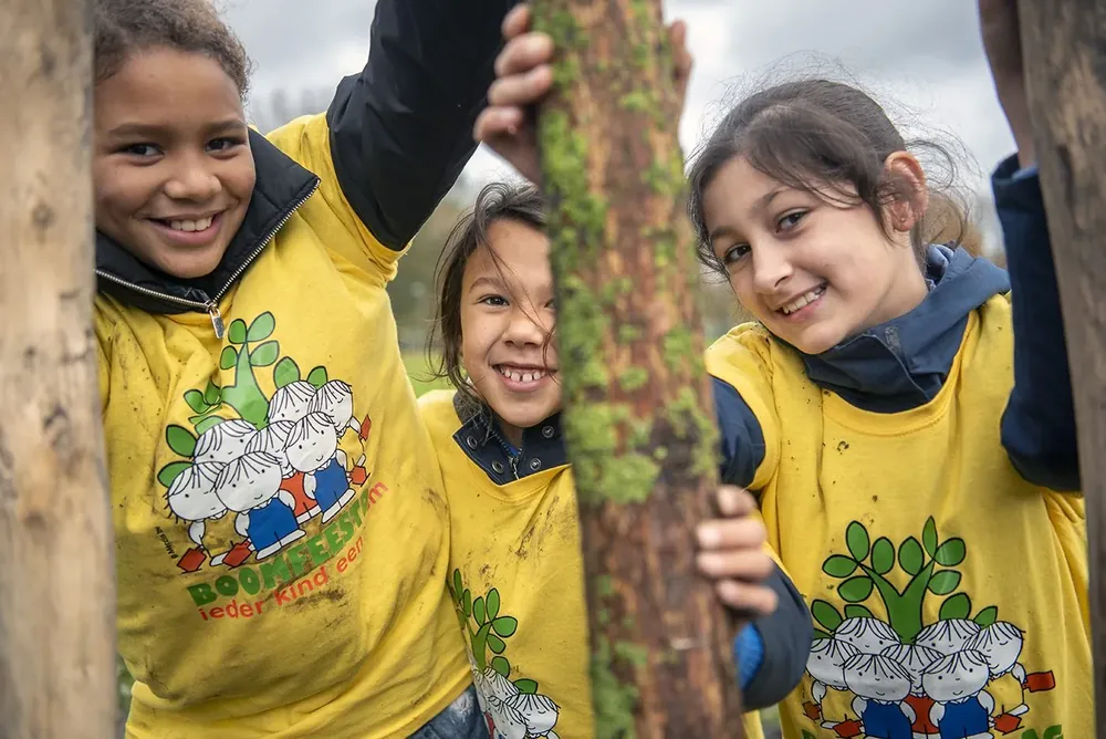 Kinderen zijn samen met een boomplantschep in de weer op een plantlocatie.
