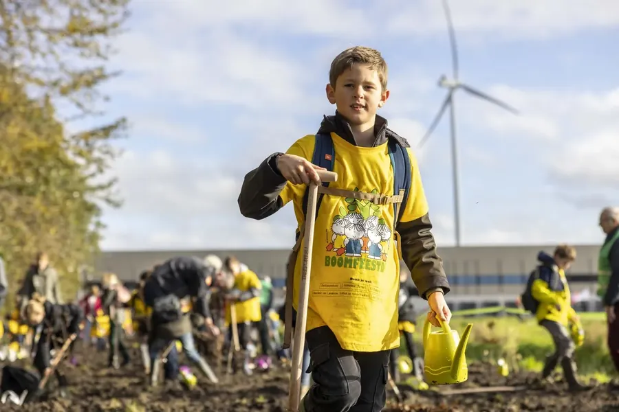 Kinderen planten jonge bomen langs de rand van een akker.
