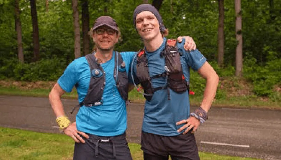 Twee hardlopers in sportkleding staan naast elkaar op een bospad.